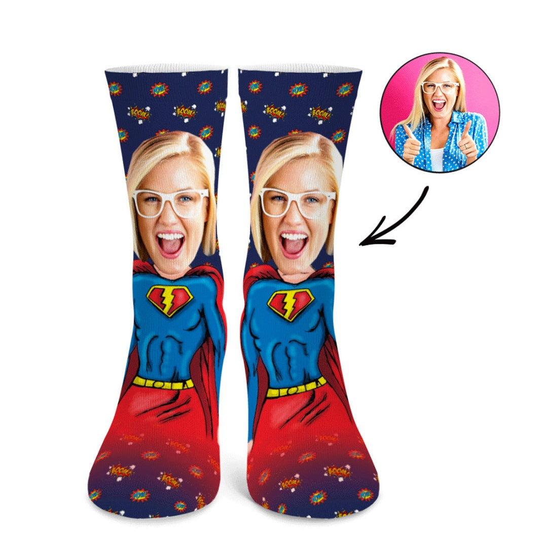 Superman-themed socks with a printed face design and a person giving a thumbs-up in a small inset.