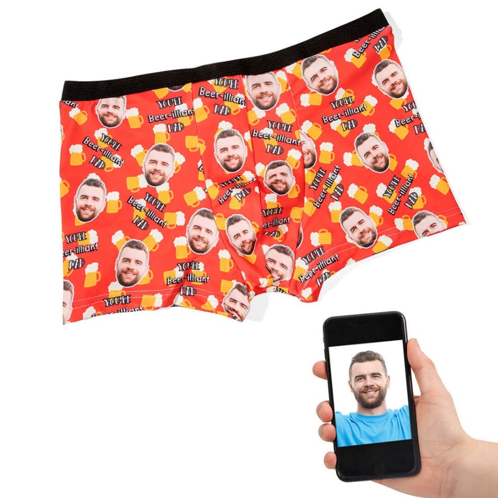 Red boxer briefs with multiple faces printed on them, held by a hand with a phone displaying a face.