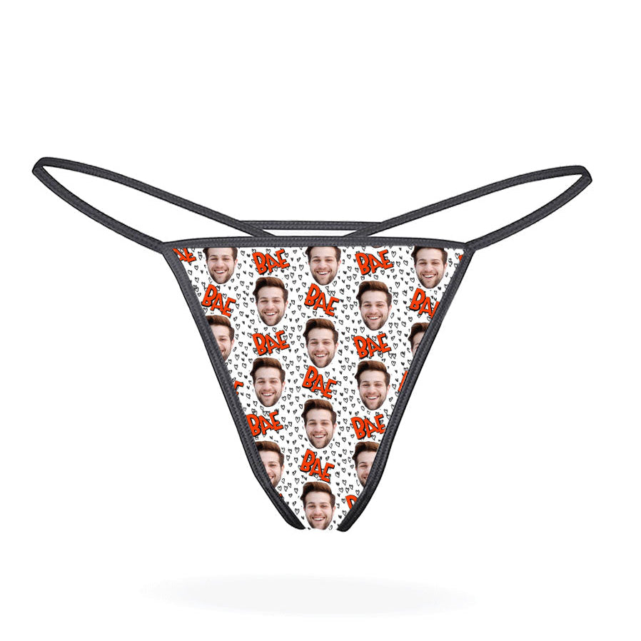 This image displays the "Bae Custom Thong," a personalized lingerie piece designed for a unique and intimate gift. The thong features a playful pattern of cartoonish faces, set against a vibrant multicolored background, adding a fun and whimsical touch.