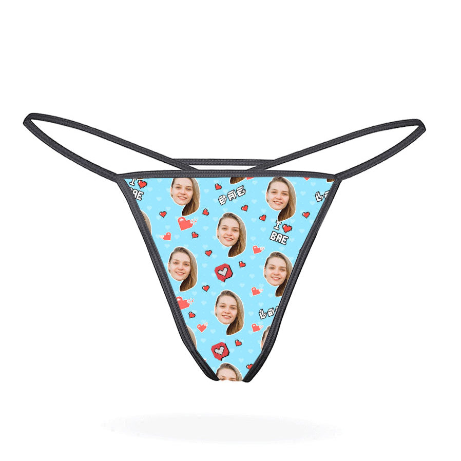This image features a custom thong designed with a vibrant, personalized print. The thong has a bright yellow background adorned with multiple cartoonish faces in various expressions, creating a playful and eye-catching look.