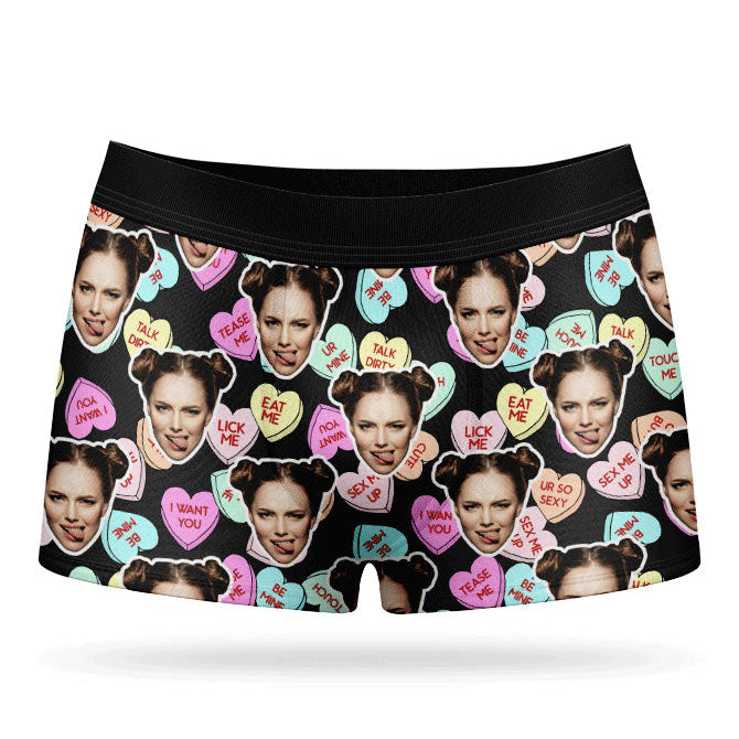 This image displays a pair of custom boxer shorts designed with a vibrant and playful print of love hearts and sweets. The boxers feature a bright pink background, adorned with images of a woman's face and various candies, adding a unique and cheeky touch.