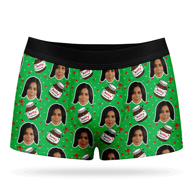 A pair of blue custom boxer shorts with a repeated pattern of a person's face and text, presumably a name, along with nuts and ice cream motifs.