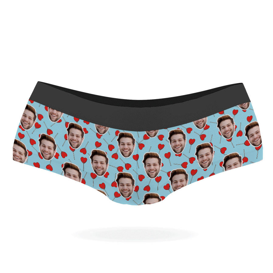 A pair of custom panties with a pattern of a person's face and heart-shaped lollipops on a black background.