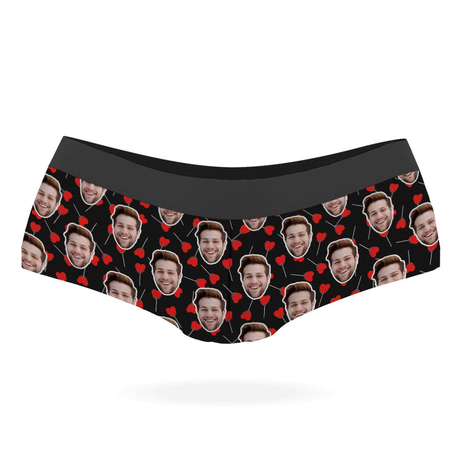 A pair of custom panties with a pattern of a person's face and heart-shaped lollipops on a black background.