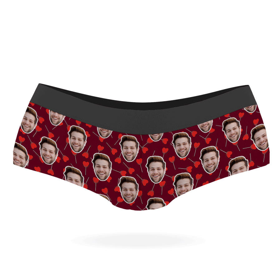 A pair of custom panties with a pattern of a person's face and heart-shaped lollipops on a black background.