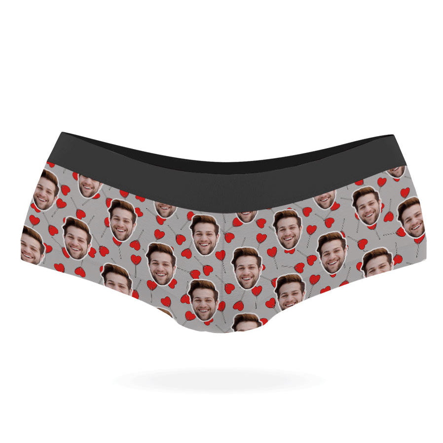 A pair of custom panties with a pattern of a person's face and heart-shaped lollipops on a black background.