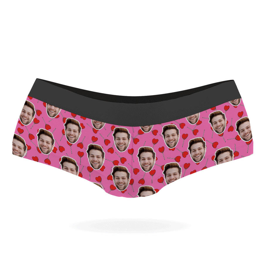 A pair of custom panties with a pattern of a person's face and heart-shaped lollipops on a black background.