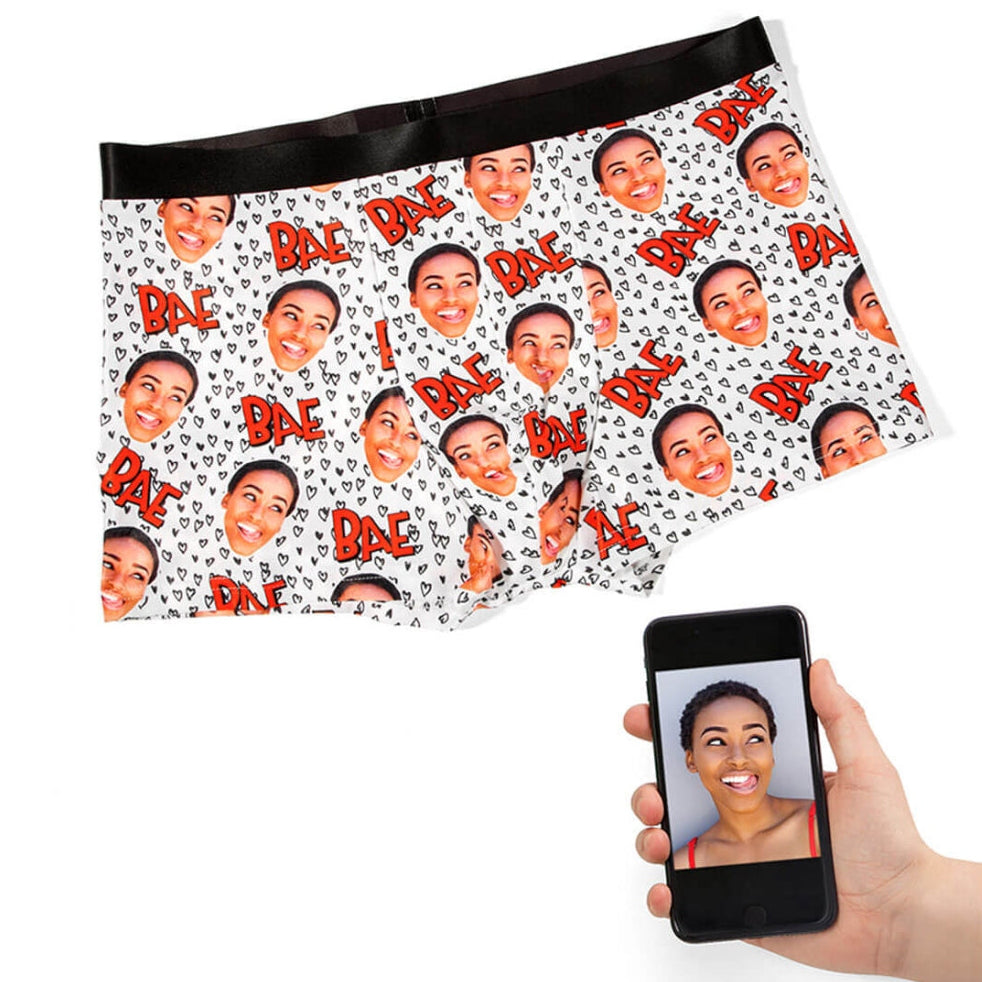 Boxer briefs with a pattern of a smiling face and 'Bac' text, held by a hand with a phone.